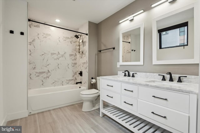 bathroom with double vanity, shower / bath combination, toilet, and a sink