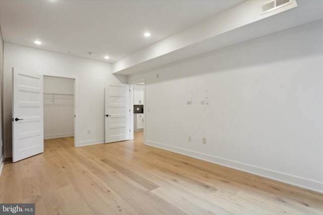 unfurnished bedroom featuring a spacious closet, visible vents, baseboards, light wood-type flooring, and recessed lighting