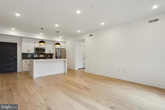 kitchen featuring tasteful backsplash, visible vents, a kitchen island, light wood-type flooring, and appliances with stainless steel finishes