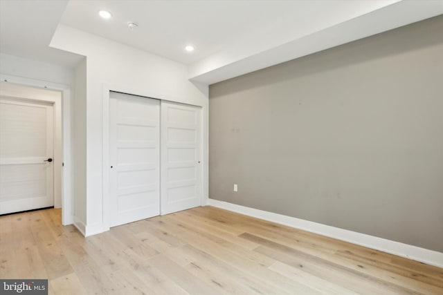 unfurnished bedroom with a closet, recessed lighting, light wood-type flooring, and baseboards