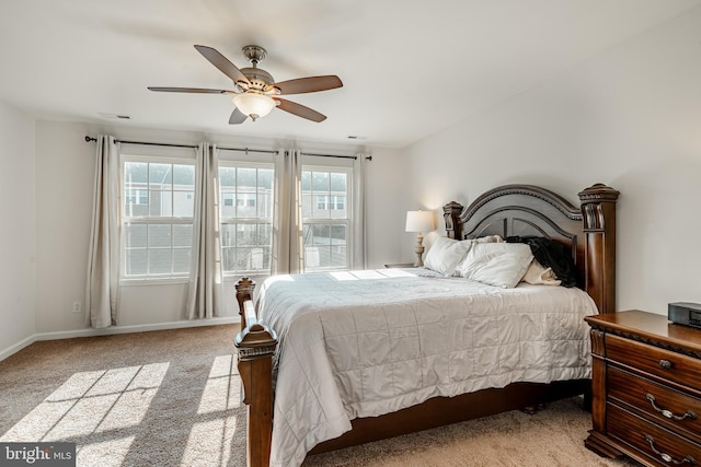 carpeted bedroom with visible vents, baseboards, and a ceiling fan