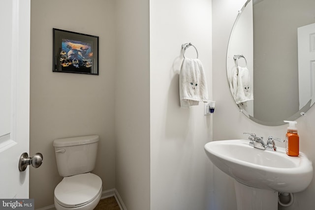 bathroom with toilet, baseboards, and a sink