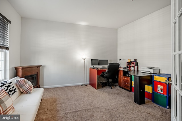 office featuring a glass covered fireplace, carpet, and baseboards