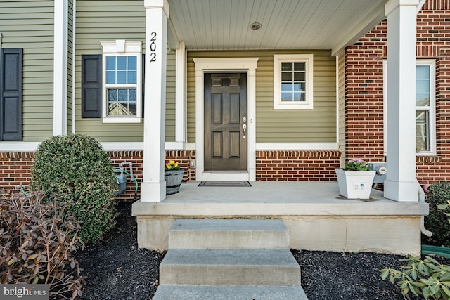 doorway to property featuring brick siding and covered porch