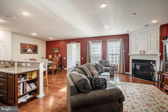 living area featuring recessed lighting, light wood-type flooring, baseboards, and a fireplace