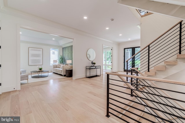 foyer entrance with a wealth of natural light, stairway, light wood-style floors, and ornamental molding