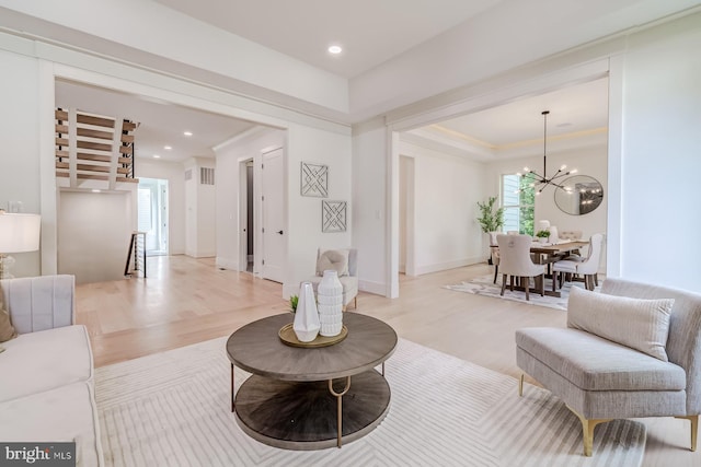 living area with a chandelier, light wood-style flooring, and ornamental molding