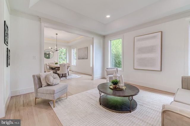 living area featuring baseboards, a chandelier, light wood-type flooring, recessed lighting, and a raised ceiling