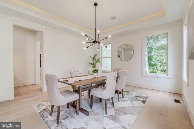 dining room featuring light wood finished floors, visible vents, a notable chandelier, and a tray ceiling