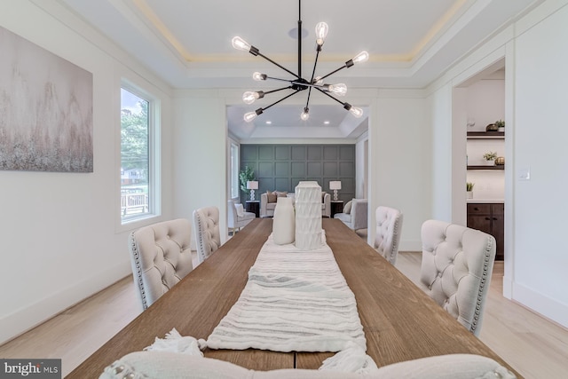 dining space featuring wood finished floors, baseboards, a tray ceiling, ornamental molding, and a chandelier