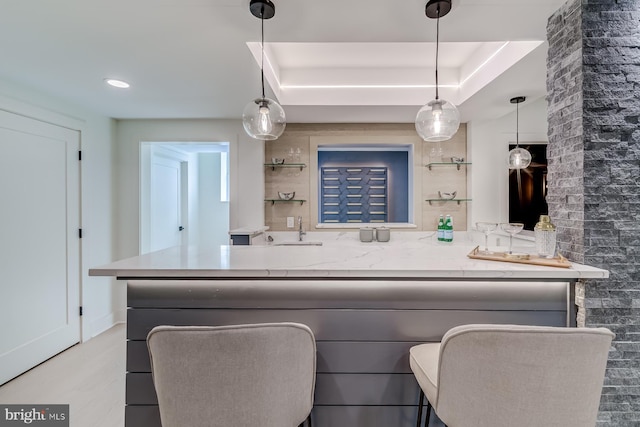 kitchen with wood finished floors, open shelves, hanging light fixtures, light countertops, and a raised ceiling