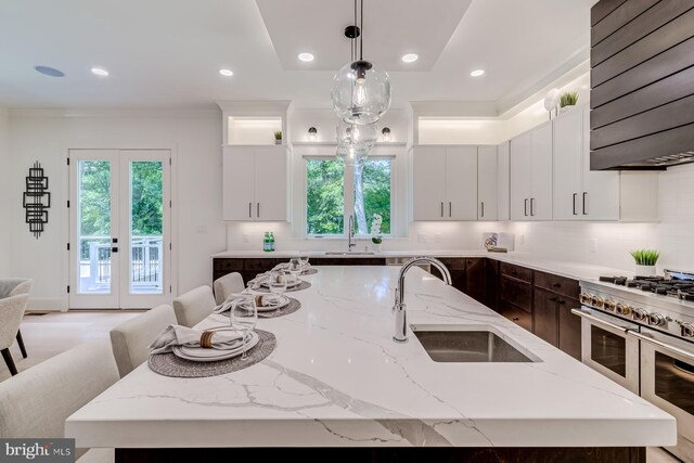 kitchen with a sink, double oven range, dark brown cabinets, and exhaust hood