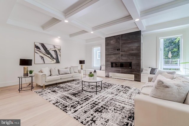 living area featuring a wealth of natural light, coffered ceiling, a large fireplace, and wood finished floors