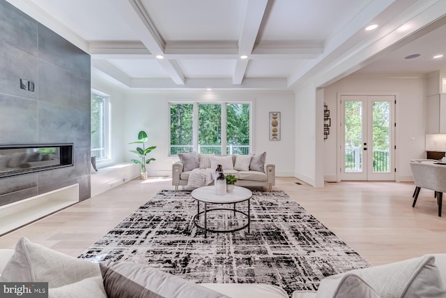 living area featuring beam ceiling, a fireplace, a wealth of natural light, and wood finished floors