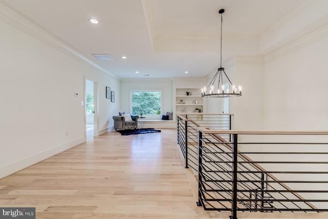 hallway with crown molding, baseboards, light wood-type flooring, an upstairs landing, and an inviting chandelier