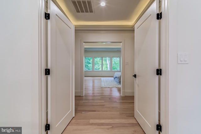 hallway featuring light wood finished floors, visible vents, and baseboards