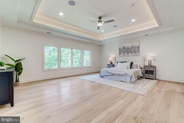 bedroom featuring a tray ceiling, baseboards, and light wood finished floors