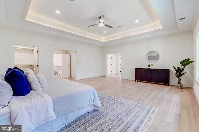 bedroom with visible vents, a raised ceiling, baseboards, and light wood-style flooring