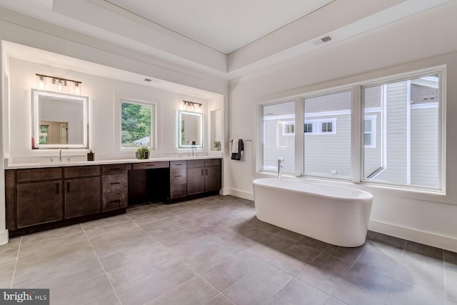 full bathroom featuring tile patterned flooring, vanity, baseboards, and a freestanding tub