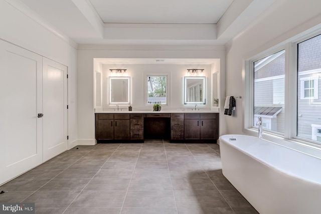 full bathroom with tile patterned floors, a soaking tub, vanity, and a raised ceiling