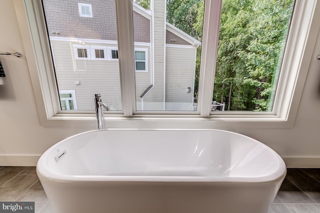 bathroom featuring tile patterned flooring, a freestanding bath, and baseboards