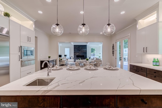 kitchen featuring built in appliances, crown molding, a warming drawer, and a sink