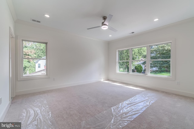 unfurnished room featuring visible vents, a healthy amount of sunlight, carpet, and ornamental molding