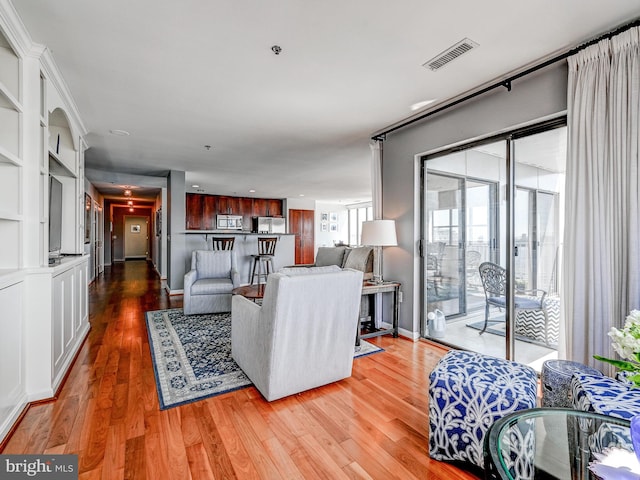 living room with baseboards, visible vents, and light wood-type flooring