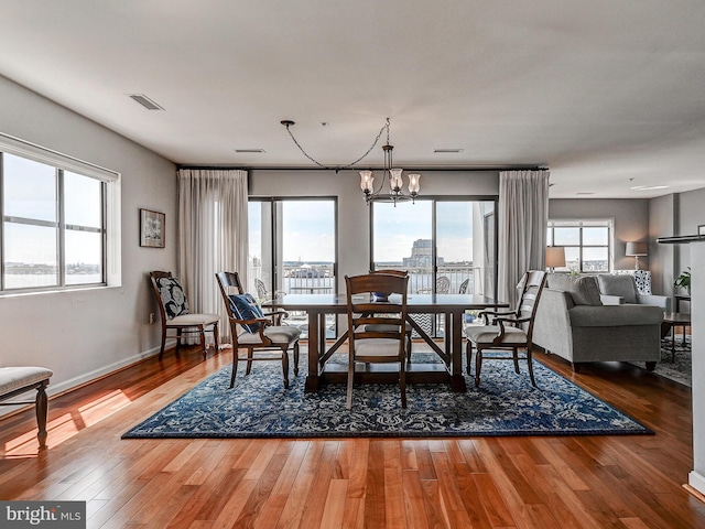 dining area featuring hardwood / wood-style flooring, baseboards, visible vents, and a chandelier