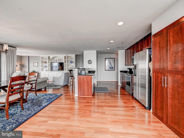 kitchen with light wood-style flooring, dark countertops, appliances with stainless steel finishes, and open floor plan