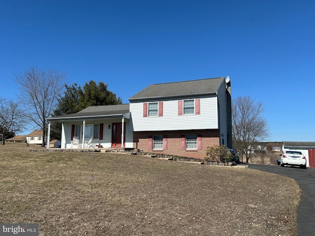 split level home with a porch, brick siding, and driveway