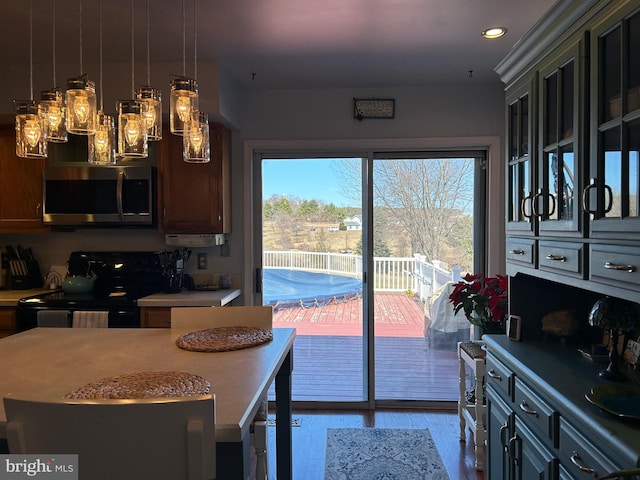 kitchen featuring hanging light fixtures, stainless steel microwave, black electric range oven, and light countertops