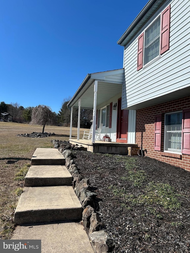 view of side of home featuring brick siding and a porch