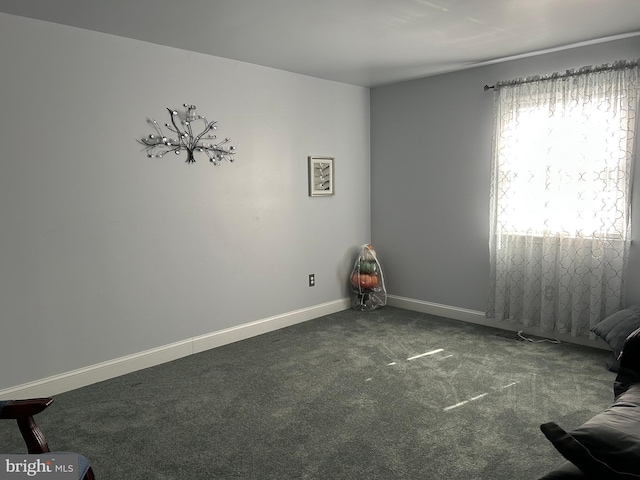 empty room with dark carpet and baseboards