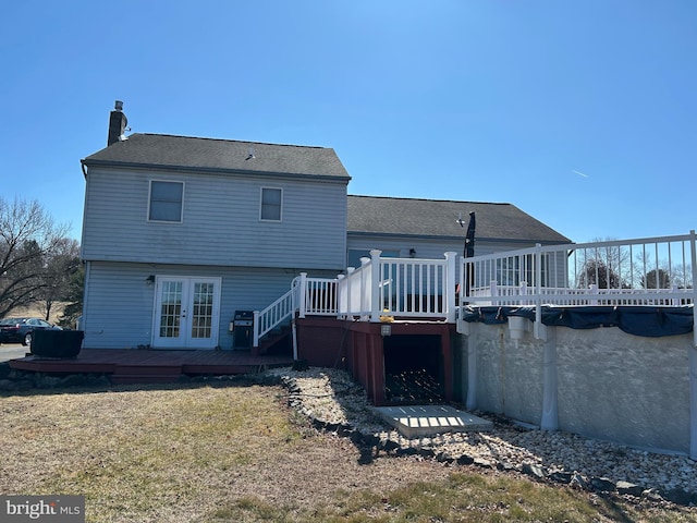 back of property featuring french doors, a lawn, a wooden deck, and a chimney