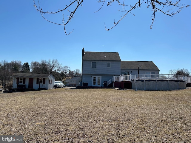 back of property with a covered pool, french doors, a wooden deck, and a chimney