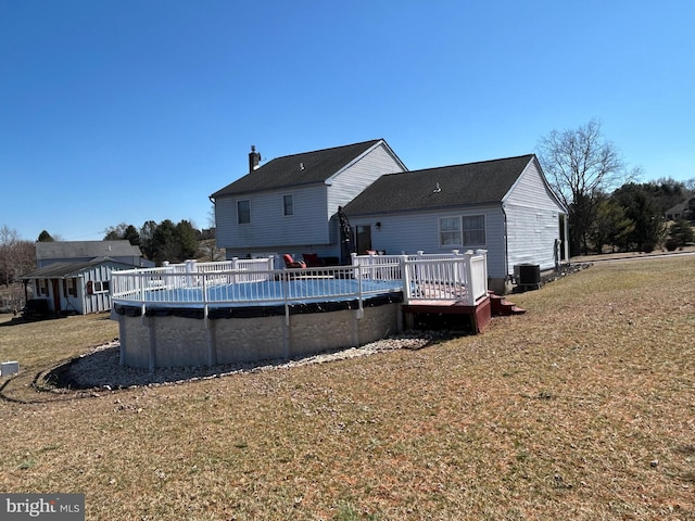 back of house featuring a deck, a yard, cooling unit, and an outdoor pool