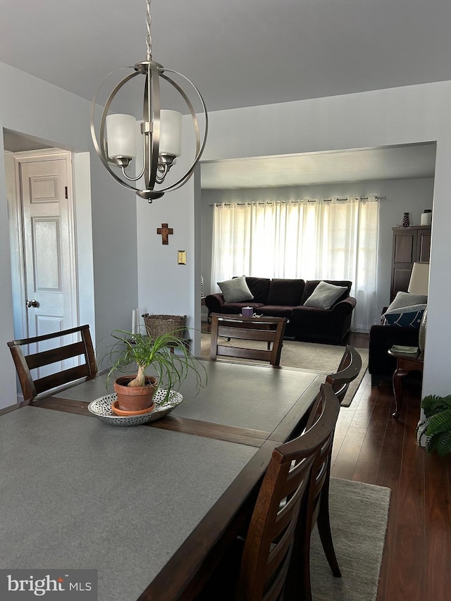 dining room with dark wood-style floors and a notable chandelier