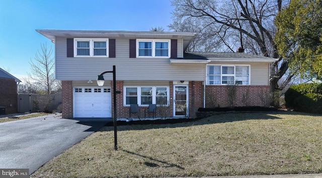 tri-level home featuring brick siding, driveway, a front lawn, and a garage