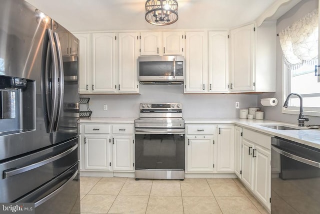 kitchen with appliances with stainless steel finishes, white cabinetry, light countertops, and a sink