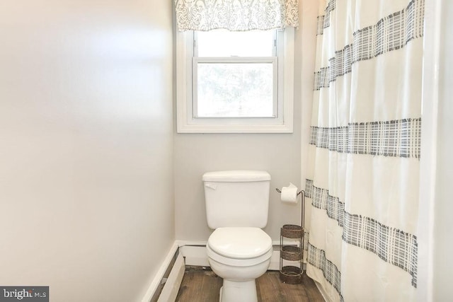 bathroom with a shower with curtain, toilet, wood finished floors, and baseboards