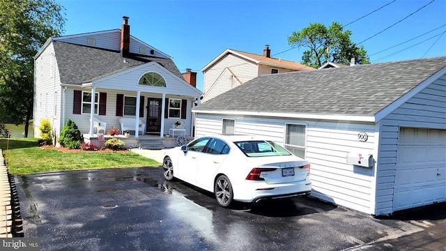 view of front facade featuring a front lawn, a garage, covered porch, and roof with shingles