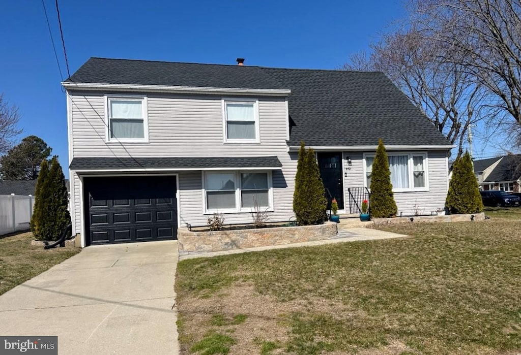 traditional home with a garage, driveway, a shingled roof, and a front yard