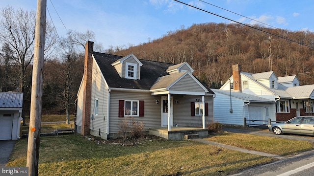 view of front of house with an attached garage, a chimney, and a front lawn