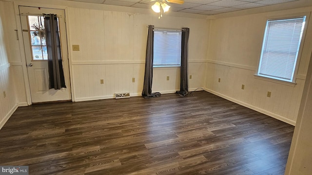 empty room featuring visible vents, dark wood-type flooring, a ceiling fan, baseboards, and a paneled ceiling