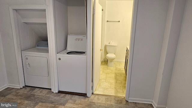 clothes washing area with baseboards, stone finish floor, laundry area, and washing machine and clothes dryer