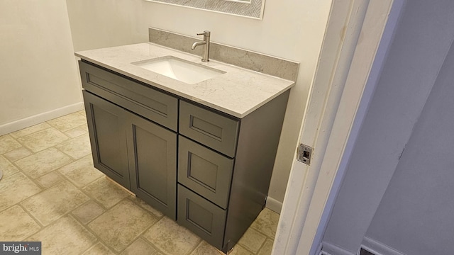 bathroom featuring baseboards, vanity, and stone finish floor