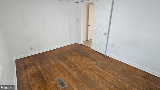 unfurnished room with visible vents, wood-type flooring, and baseboards