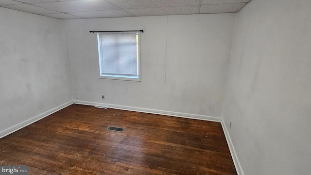 unfurnished room with visible vents, baseboards, dark wood-type flooring, and a paneled ceiling