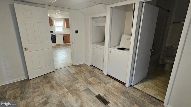 washroom with baseboards, visible vents, laundry area, washing machine and dryer, and light wood-type flooring